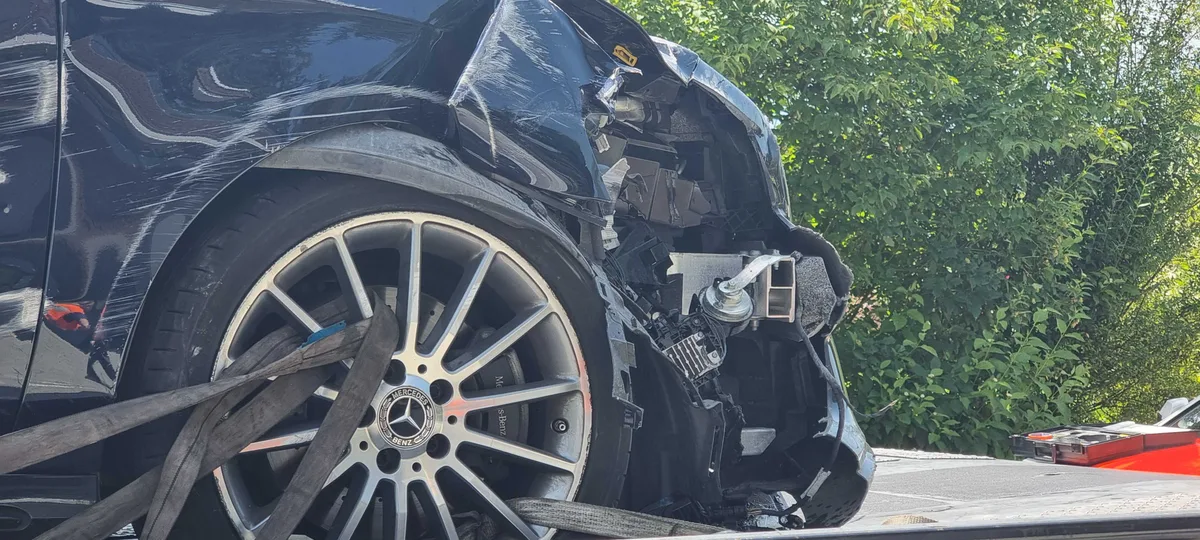 Ein grosser Blechschaden, der sich wohl nicht so einfach reparieren lässt. Man sieht eine Unfallstelle und ein stark beschädigtes Unfallauto.
